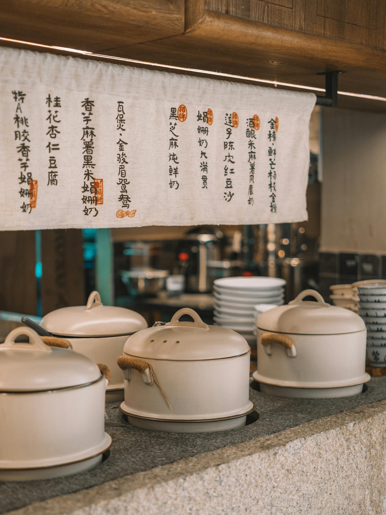 A cozy Asian kitchen scene featuring ceramic pots and menu in calligraphy.