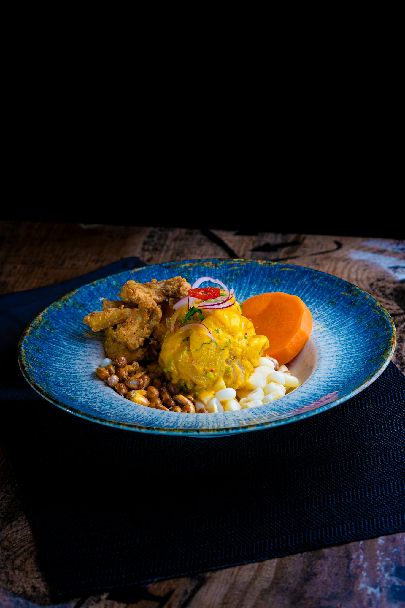 Colorful Peruvian ceviche dish with sweet potato and corn served on a rustic plate.
