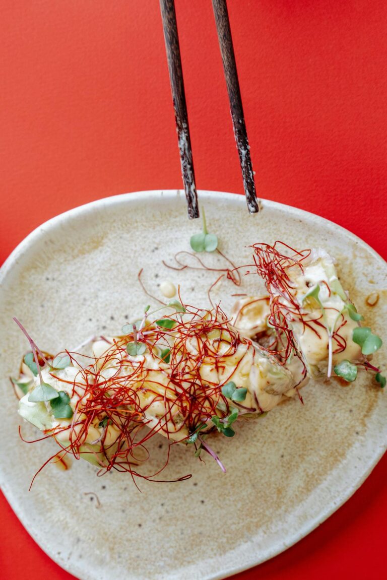 Tasteful Asian fusion dish with artistic garnish on a red background, top view.